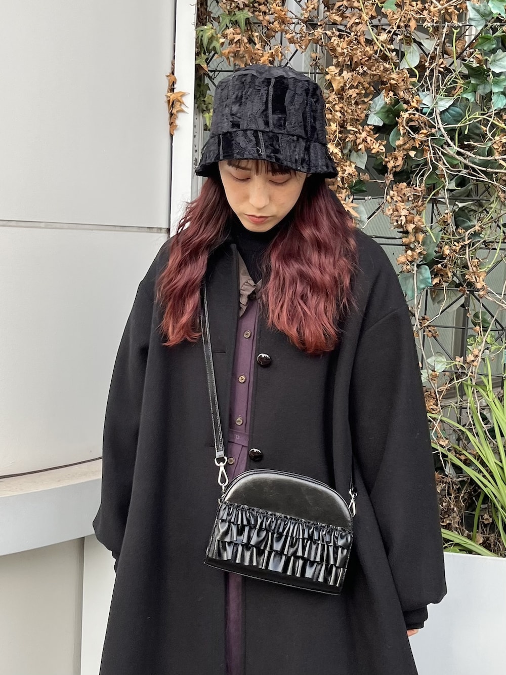 パープル系のワンピース、ブラック系のステンカラーコート、ブラック系のブーツを着用したレディースの冬コーディネートの2枚目の写真