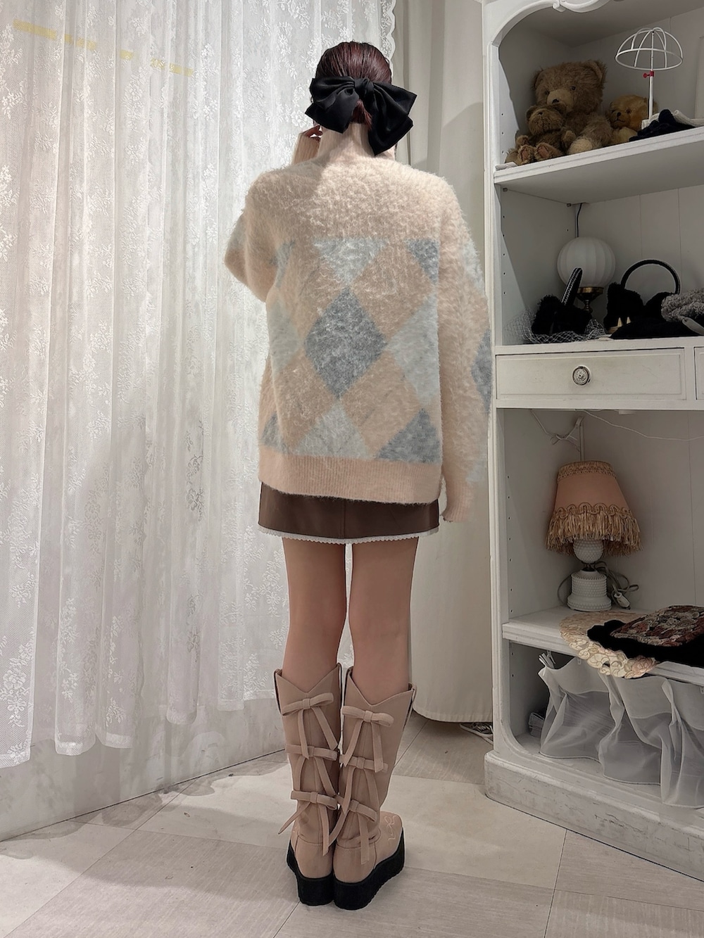 ピンク系のニット/セーター、ブラウン系のスカート、ピンク系のブーツを着用したレディースの秋コーディネートの2枚目の写真