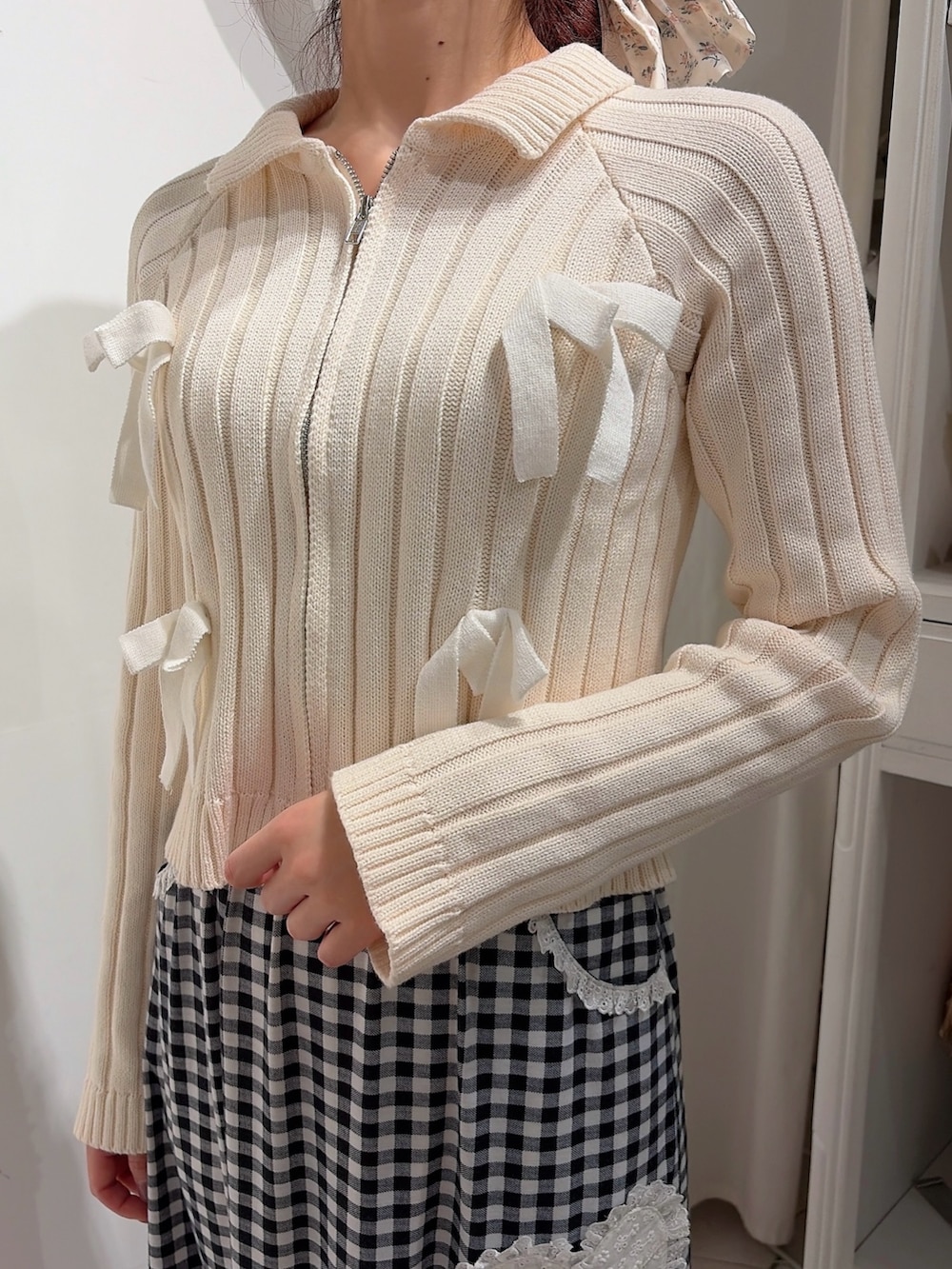 ホワイト系のカーディガン/ボレロ、ブラック系のスカート、ブラック系のスニーカーを着用したレディースの冬コーディネートの5枚目の写真