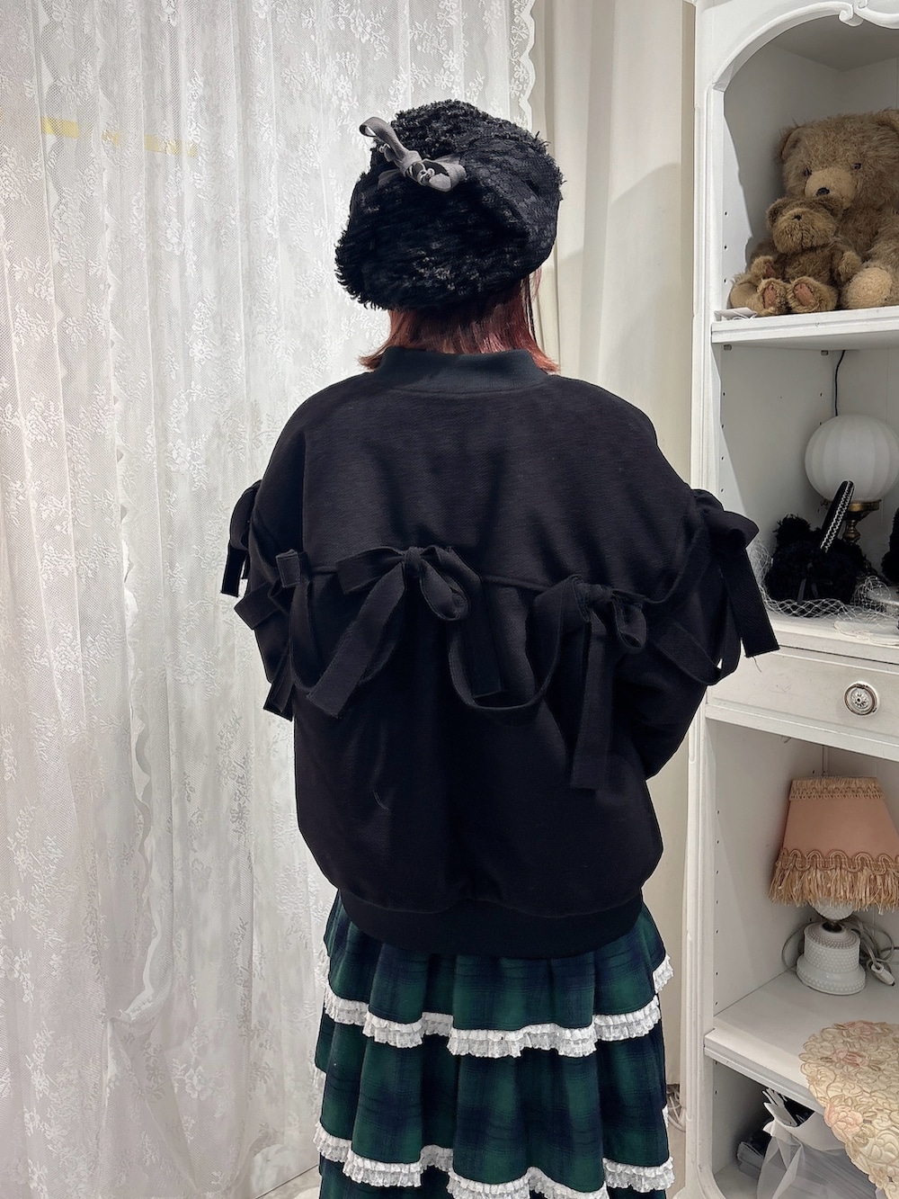 ブラック系のブルゾン、ホワイト系のニット/セーター、グリーン系のスカートを着用したレディースの秋コーディネートの4枚目の写真