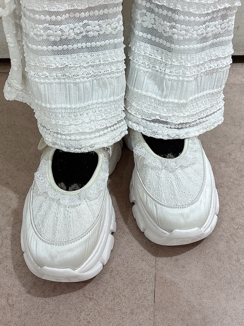 グレー系のニット/セーター、グレー系のスカート、ホワイト系のその他パンツを着用したレディースの冬コーディネートの6枚目の写真