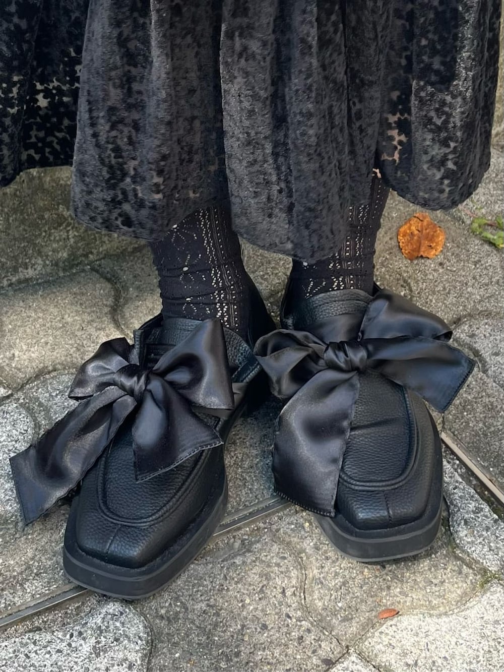 ブラック系のニット/セーター、ブラック系のスカート、ブラック系のモカシン/デッキシューズを着用したレディースの秋コーディネートの5枚目の写真