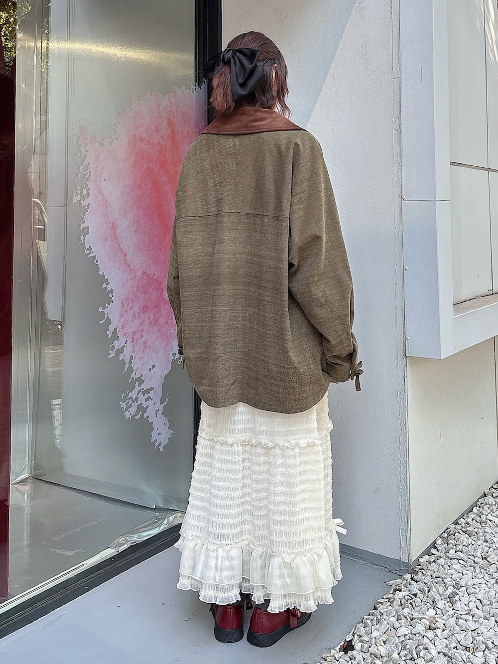 ホワイト系のスカート、ブラウン系のブルゾン、ベージュ系のTシャツ/カットソーを着用したレディースの夏コーディネートの2枚目の写真