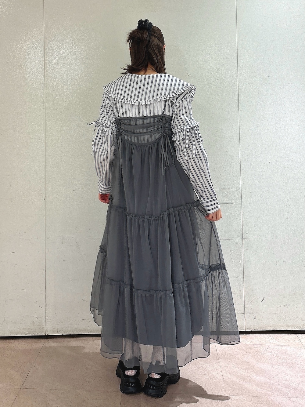 グレー系のワンピース、ホワイト系のシャツ/ブラウス、ブラック系のスニーカーを着用したレディースの夏コーディネートの2枚目の写真