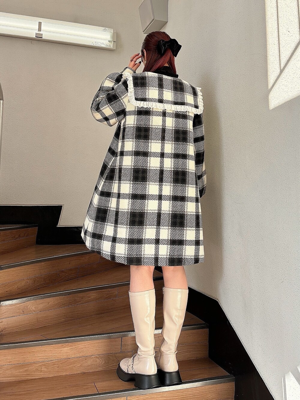 ブラック系のチェスターコート、ホワイト系のブーツ、ブラック系のニット/セーターを着用したレディースの秋コーディネートの2枚目の写真