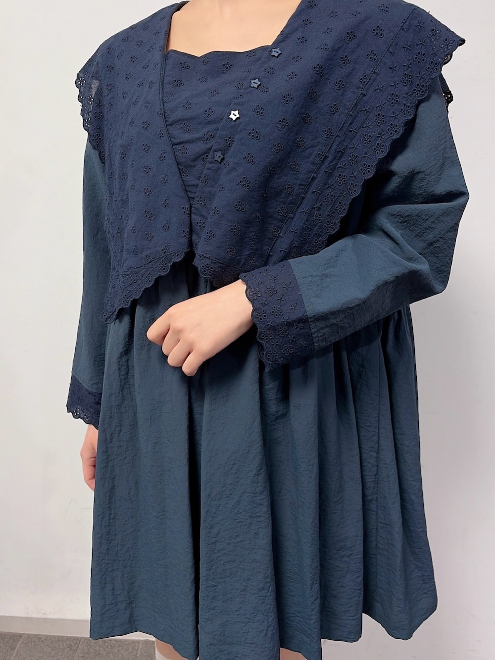 ブルー系のワンピース、ベージュ系のメッセンジャーバッグ、ブラック系のスニーカーを着用したレディースの冬コーディネートの5枚目の写真