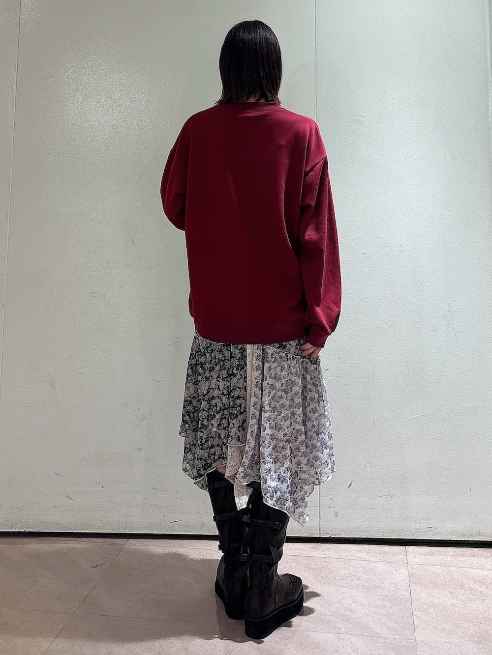 レッド系のスウェット、ブラック系のスカート、ブラウン系のブーツを着用したレディースの秋コーディネートの2枚目の写真