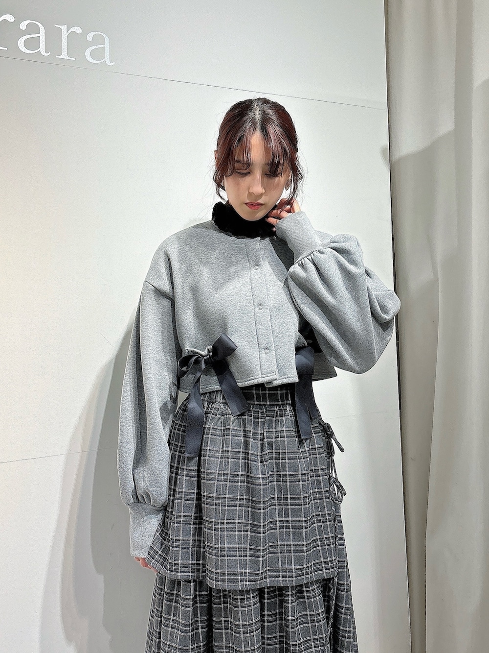 グレー系のスカート、ブラック系のスニーカー、グレー系のカーディガン/ボレロを着用したレディースの冬コーディネートの2枚目の写真