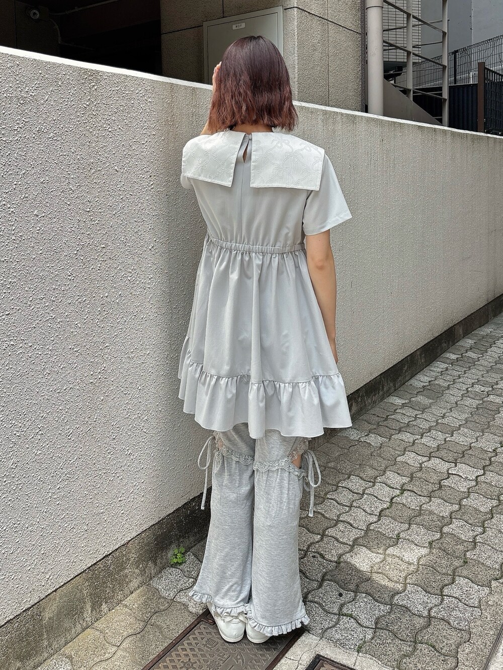 ブルー系のワンピース、グレー系のスウェットパンツ、ホワイト系のスニーカーを着用したレディースの春コーディネートの2枚目の写真