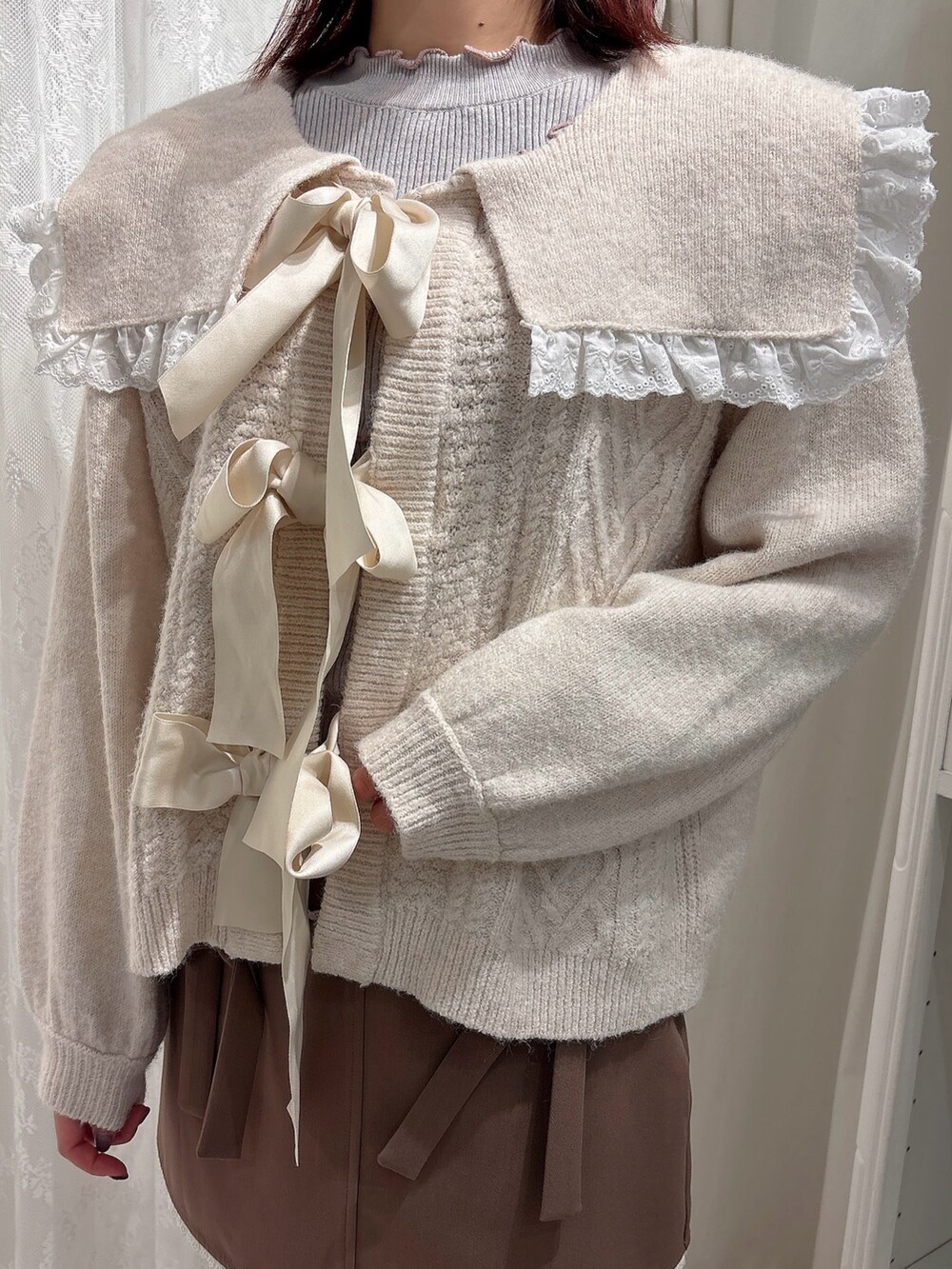 ブラウン系のスカート、ブラック系のブーツ、ホワイト系のカーディガン/ボレロを着用したレディースの秋コーディネートの5枚目の写真