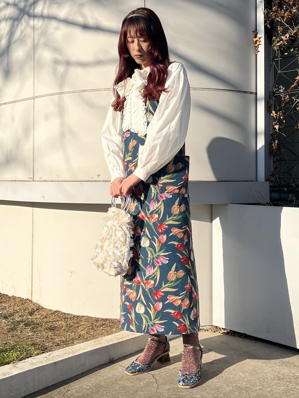 ホワイト系のシャツ/ブラウス、ブルー系のジャンパースカート、ホワイト系のハンドバッグを着用したレディースの冬コーディネートの2枚目の写真