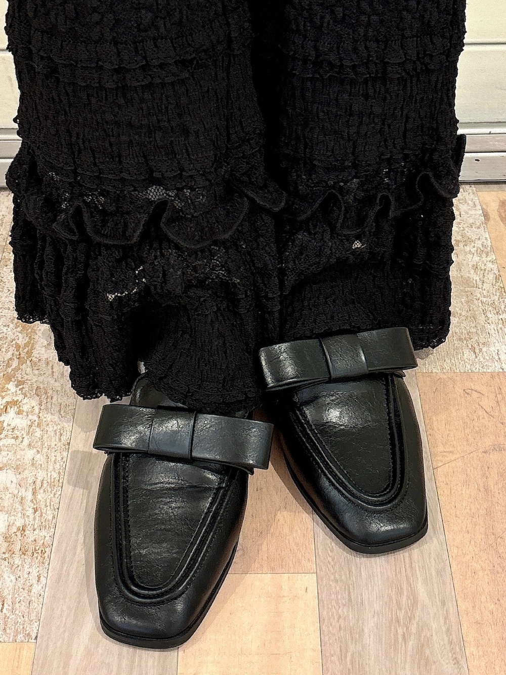 ブラック系のカーディガン/ボレロ、ブラウン系のスカート、ホワイト系のスラックスを着用したレディースの秋コーディネートの7枚目の写真