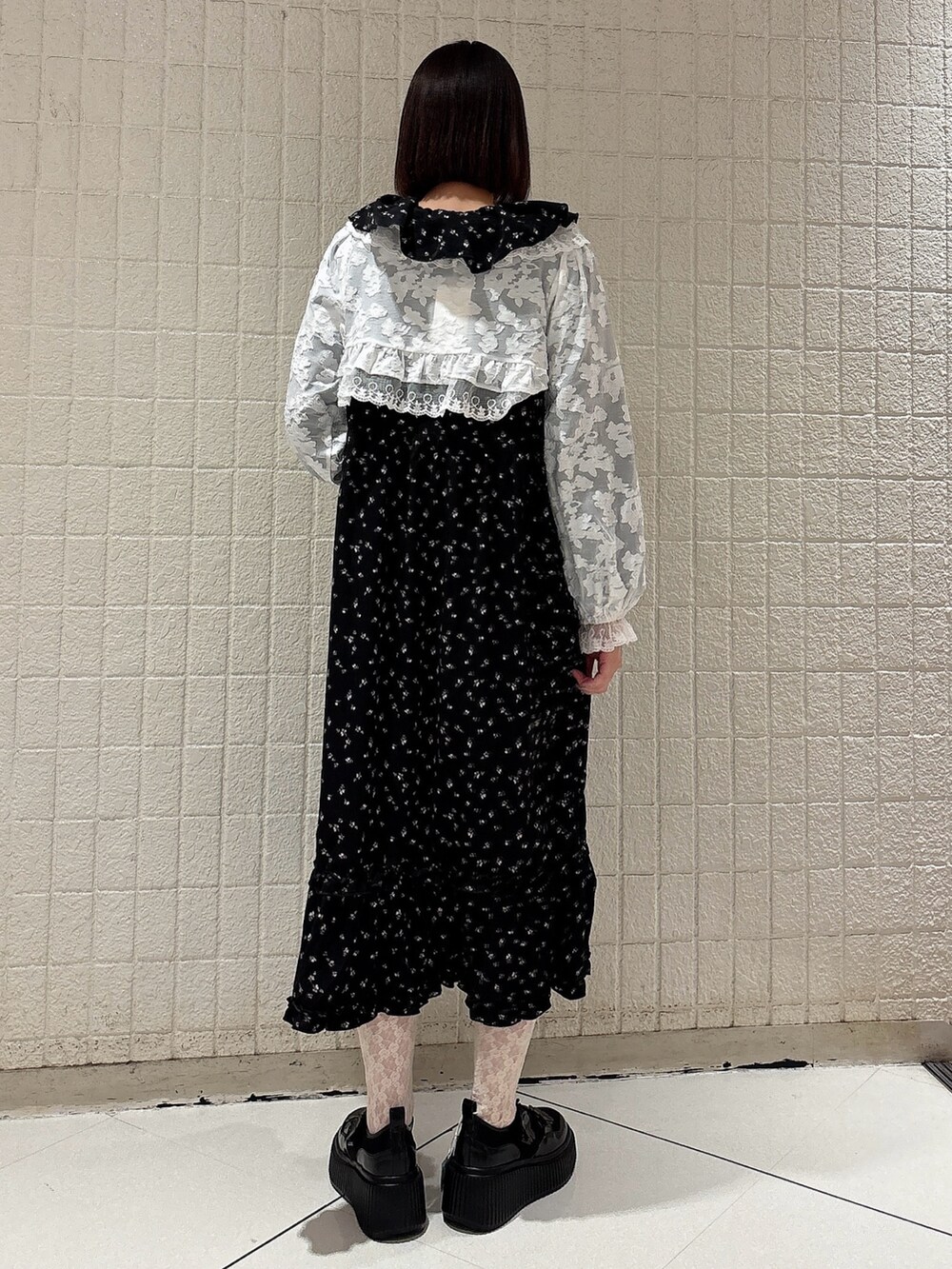 ブラック系のワンピース、ホワイト系のカーディガン/ボレロ、ブラック系のスニーカーを着用したレディースの冬コーディネートの2枚目の写真