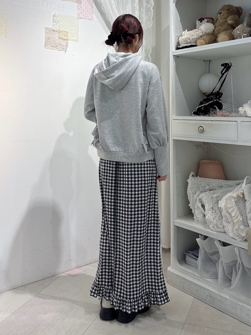 グレー系のパーカー、ブラック系のスカート、ホワイト系のスニーカーを着用したレディースの秋コーディネートの2枚目の写真