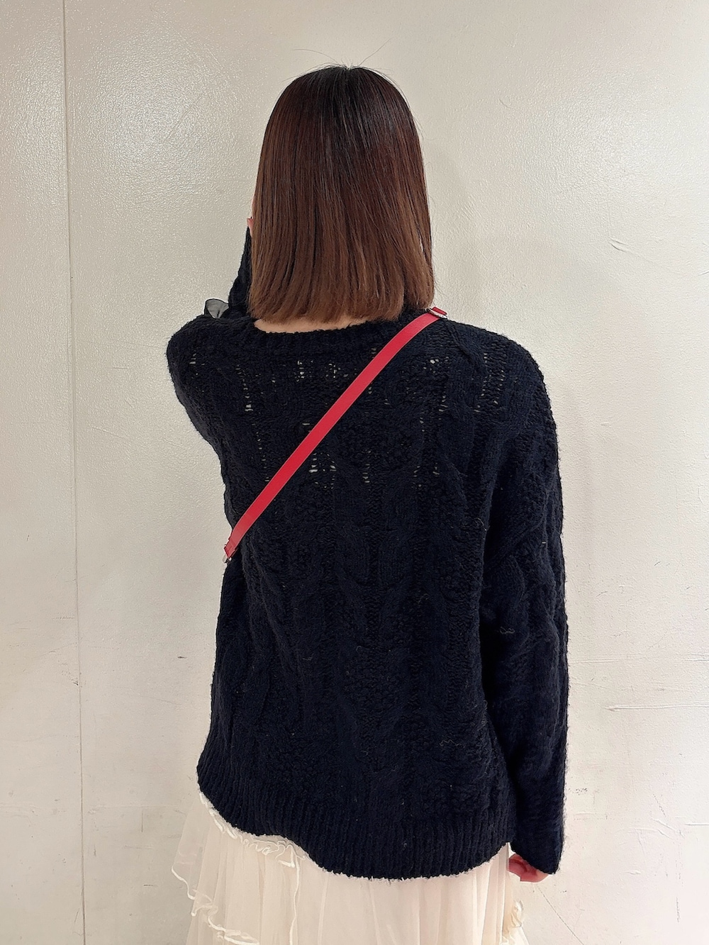 ブラック系のニット/セーター、レッド系のショルダーバッグ、ホワイト系のスカートを着用したレディースの冬コーディネートの4枚目の写真