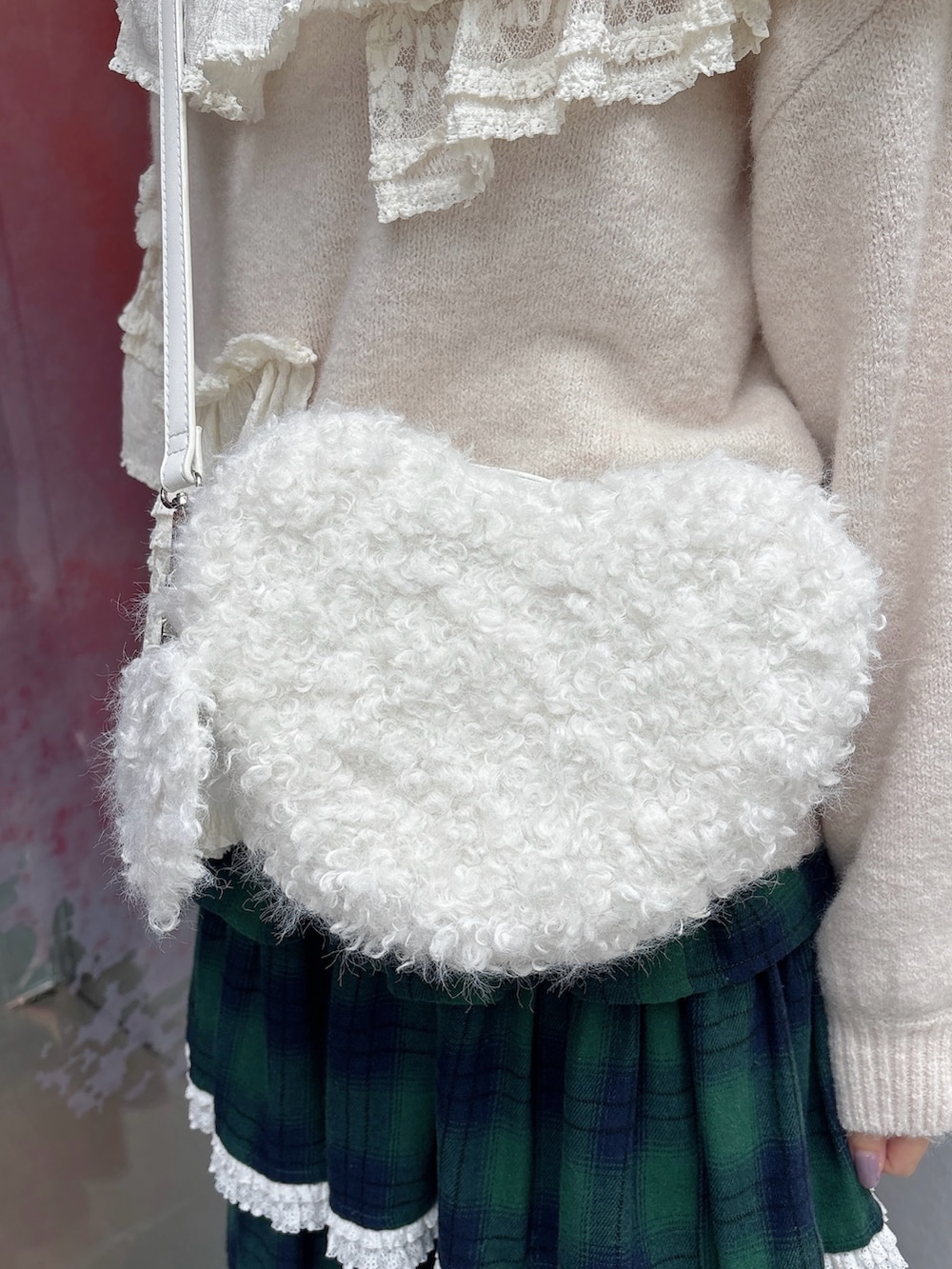 ホワイト系のニット/セーター、ホワイト系のショルダーバッグ、グリーン系のスカートを着用したレディースの秋コーディネートの7枚目の写真