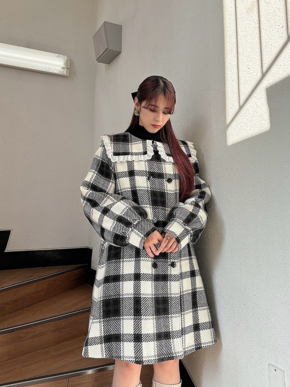 ブラック系のチェスターコート、ホワイト系のブーツ、ブラック系のニット/セーターを着用したレディースの秋コーディネートの3枚目の写真