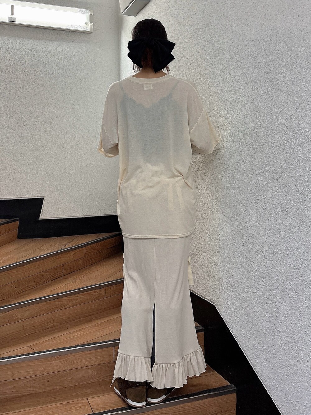 ホワイト系のTシャツ/カットソー、ホワイト系のスカート、ブラウン系のスニーカーを着用したレディースの夏コーディネートの2枚目の写真