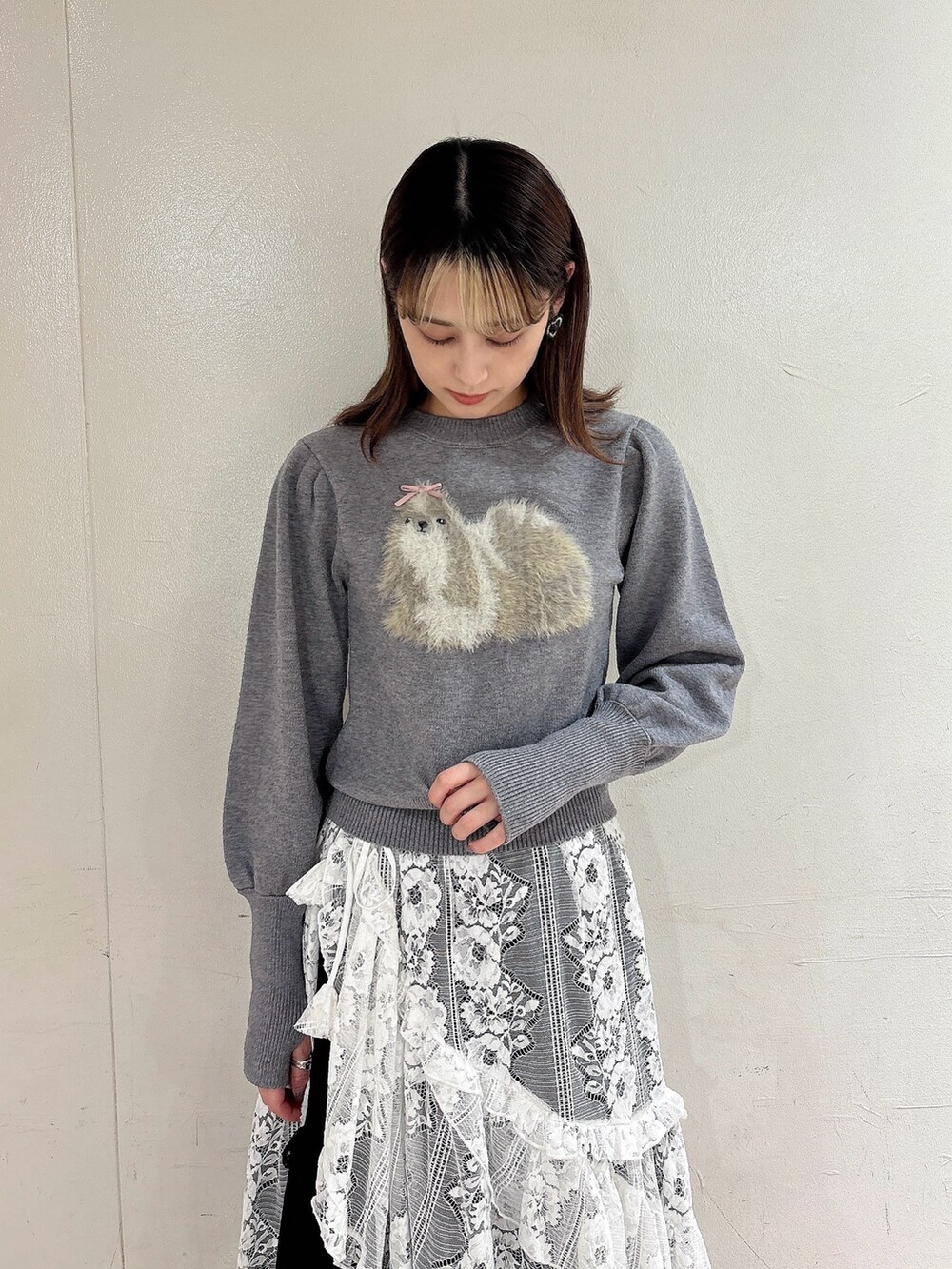 グレー系のニット/セーター、ブラック系のスカート、ホワイト系のスカートを着用したレディースの秋コーディネートの3枚目の写真