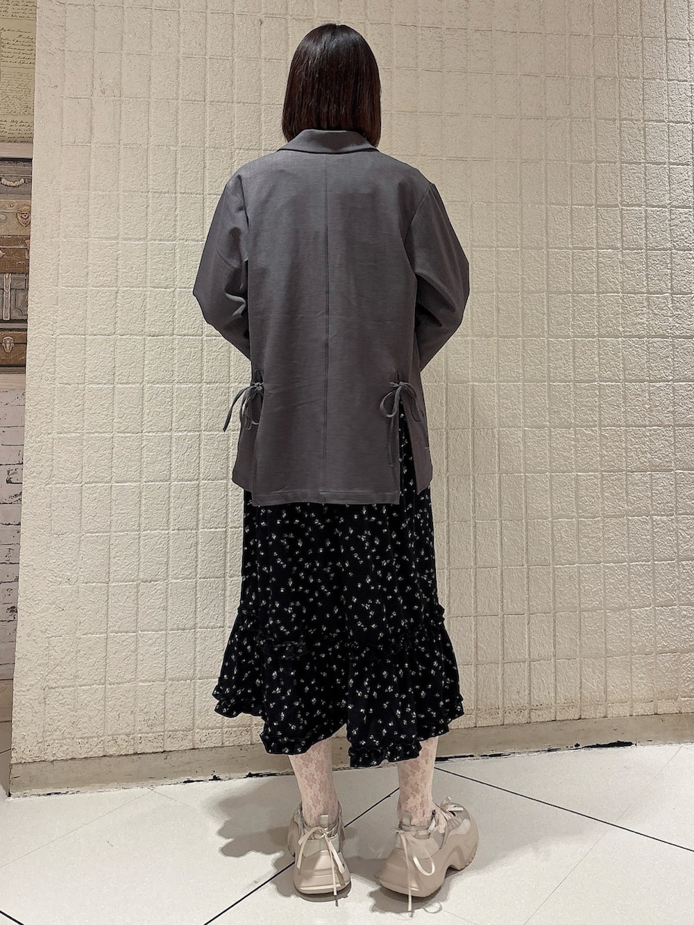 グレー系のテーラードジャケット、ブラック系のワンピースを着用したレディースの冬コーディネートの2枚目の写真