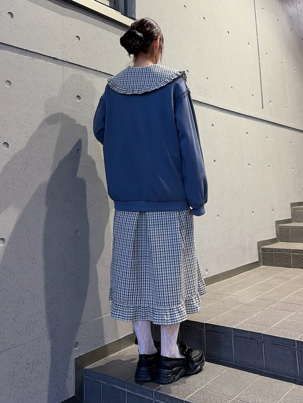 ブルー系のスウェット、ブルー系のワンピース、ブラック系のスニーカーを着用したレディースの冬コーディネートの2枚目の写真