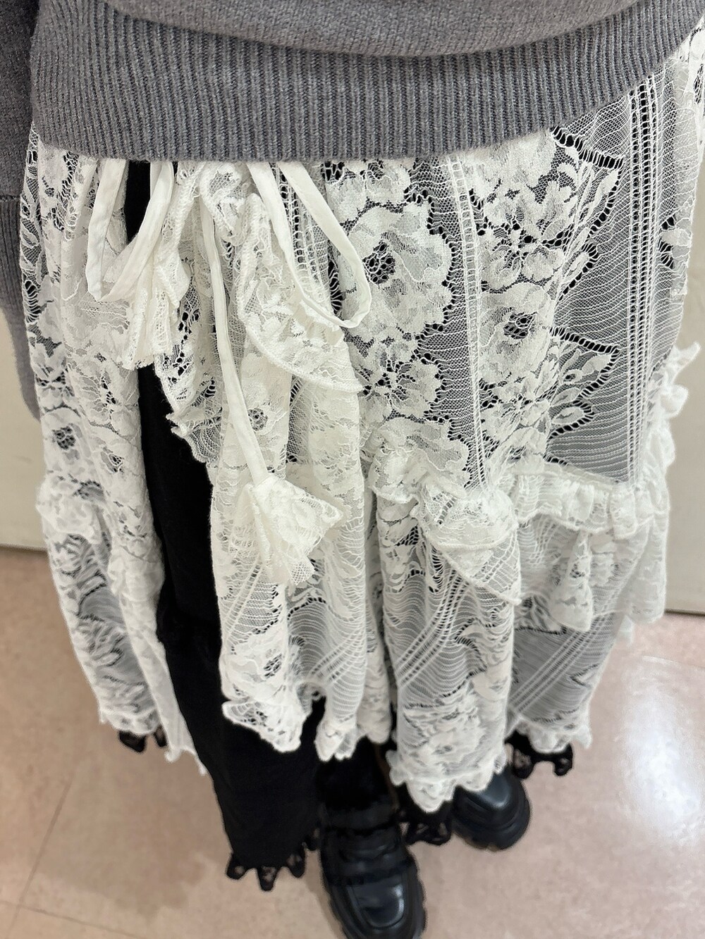 グレー系のニット/セーター、ブラック系のスカート、ホワイト系のスカートを着用したレディースの秋コーディネートの6枚目の写真