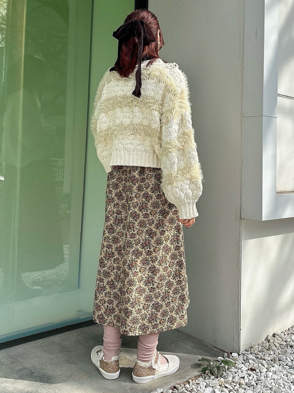 ベージュ系のジャンパースカート、ホワイト系のニット/セーター、ブラック系のニット/セーターを着用したレディースの冬コーディネートの2枚目の写真