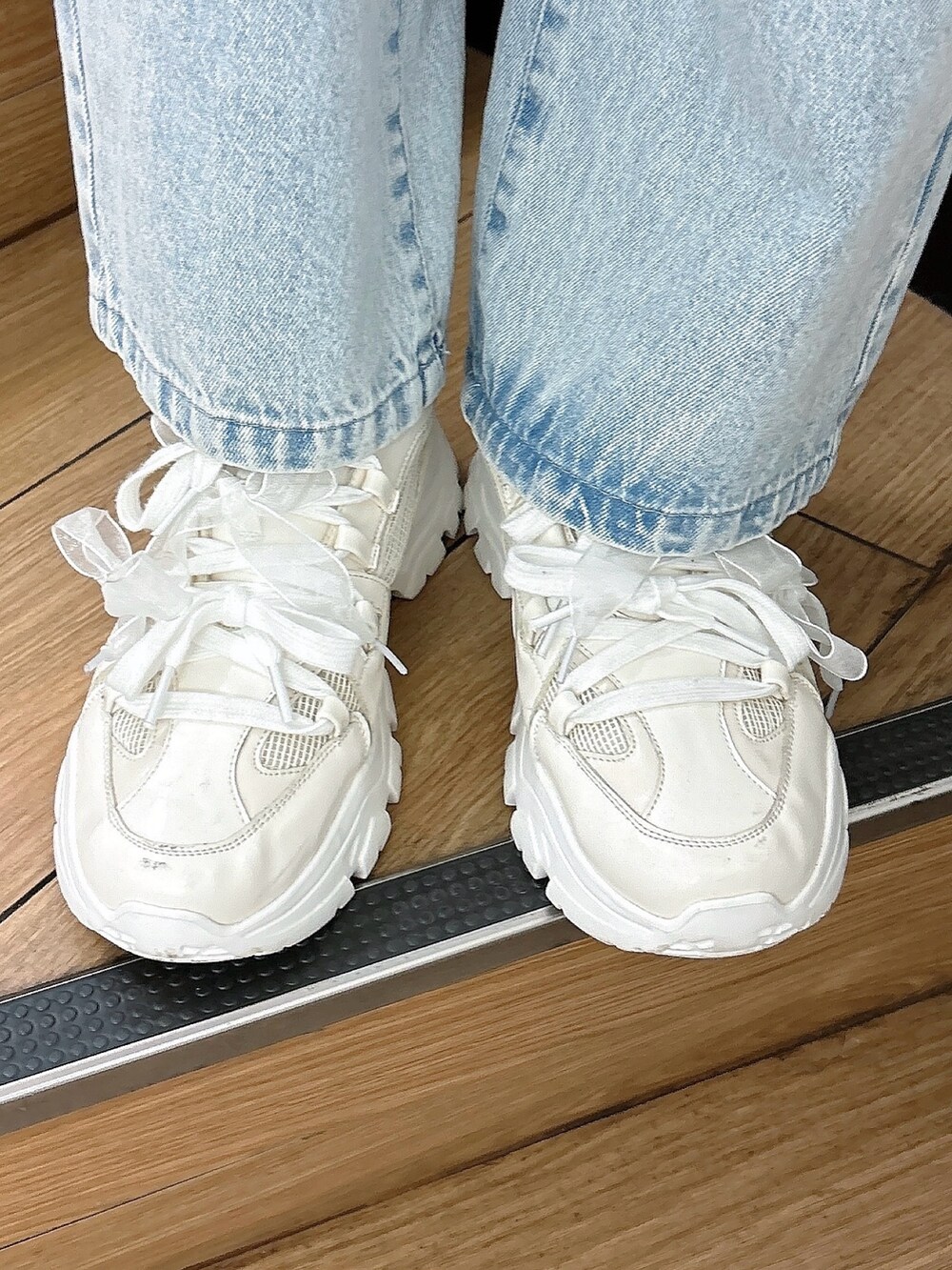 ブルー系のデニムパンツ、ホワイト系のスニーカー、グレー系のスウェットを着用したレディースの冬コーディネートの3枚目の写真