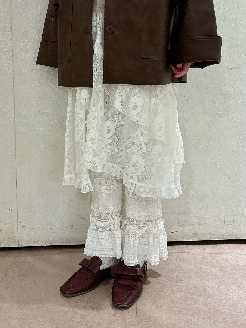 ブラウン系のブルゾン、ブラウン系のニット/セーター、ホワイト系のスカートを着用したレディースの秋コーディネートの6枚目の写真