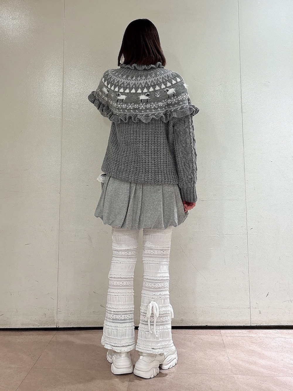 グレー系のニット/セーター、グレー系のスカート、ホワイト系のその他パンツを着用したレディースの冬コーディネートの2枚目の写真