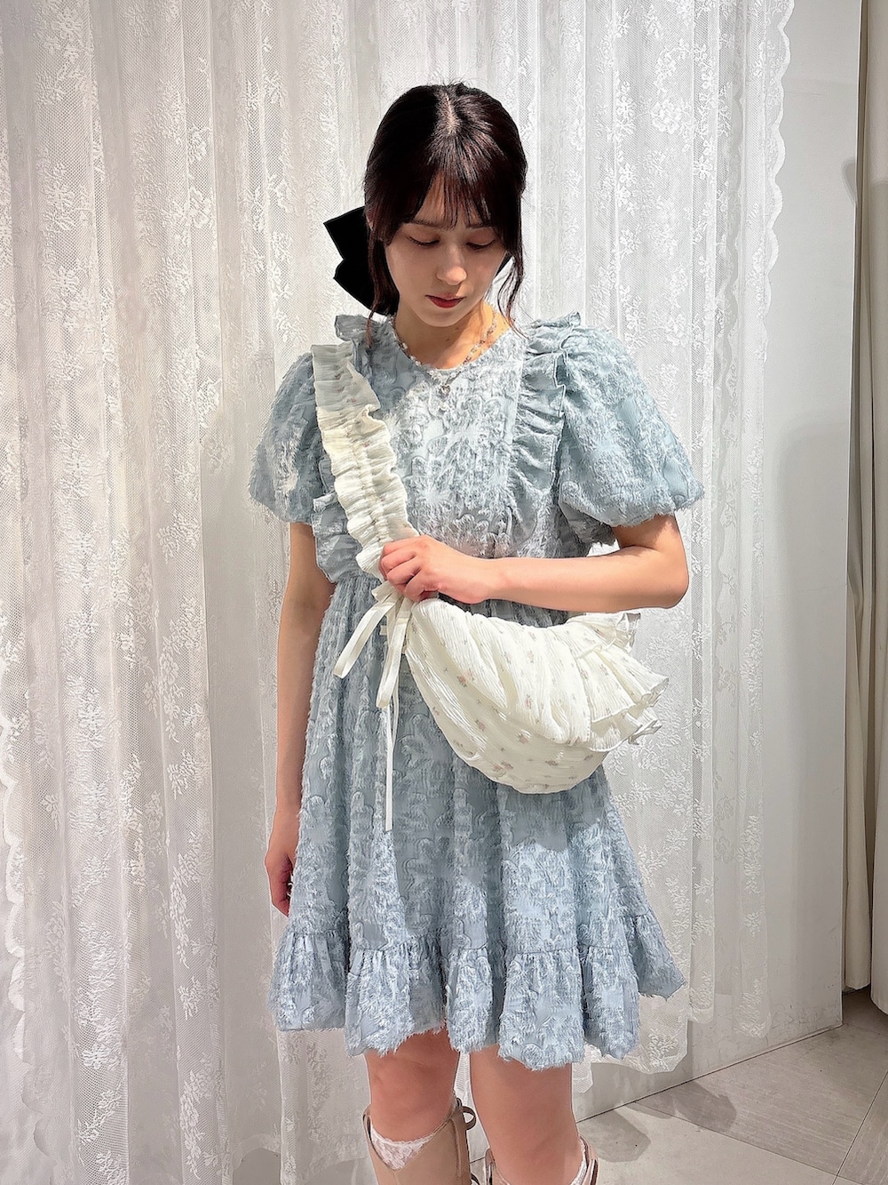 ブルー系のワンピース、ホワイト系のショルダーバッグ、ピンク系のブーツを着用したレディースの春コーディネートの3枚目の写真