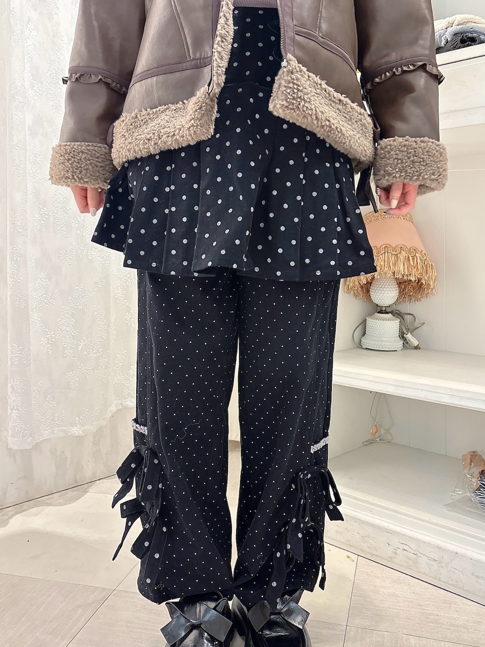 ブラウン系のムートンコート、パープル系のニット/セーター、ブラック系のスカートを着用したレディースの秋コーディネートの6枚目の写真