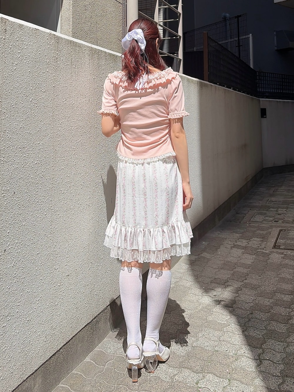 ピンク系のTシャツ/カットソー、ピンク系のスカート、ホワイト系のサンダルを着用したレディースの春コーディネートの2枚目の写真