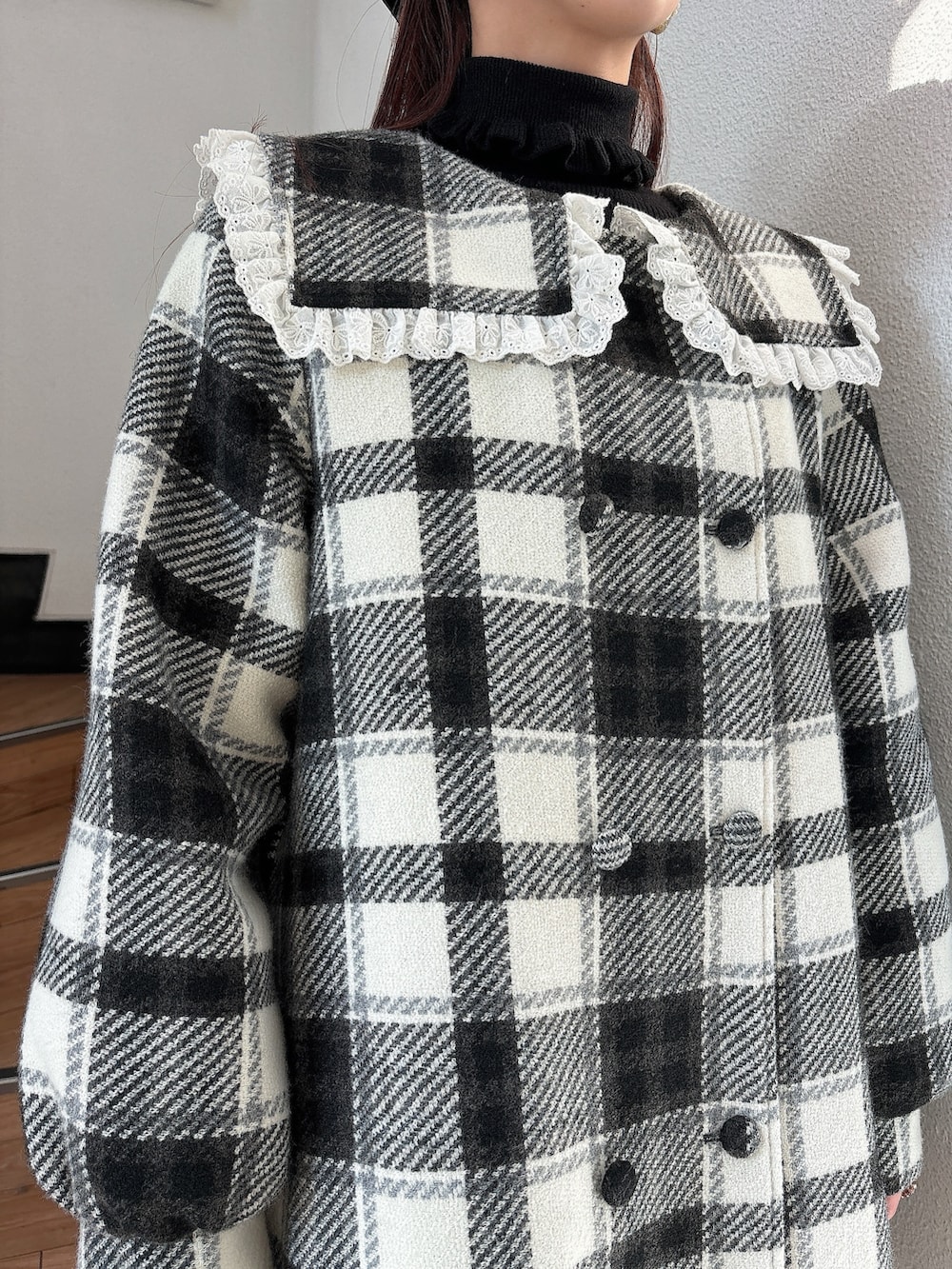 ブラック系のチェスターコート、ホワイト系のブーツ、ブラック系のニット/セーターを着用したレディースの秋コーディネートの4枚目の写真