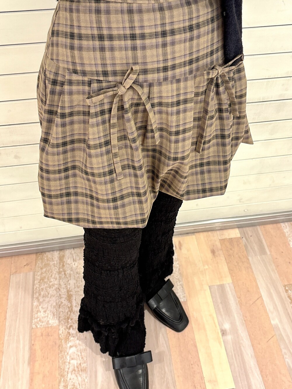 ブラック系のカーディガン/ボレロ、ブラウン系のスカート、ホワイト系のスラックスを着用したレディースの秋コーディネートの6枚目の写真