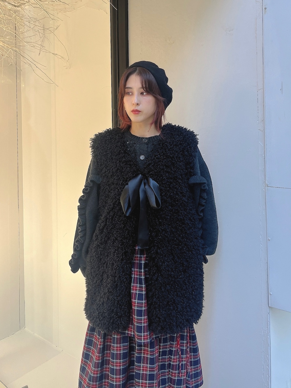 ブラック系のダウンベスト、グレー系のカーディガン/ボレロ、ブルー系のスカートを着用したレディースの秋コーディネートの2枚目の写真