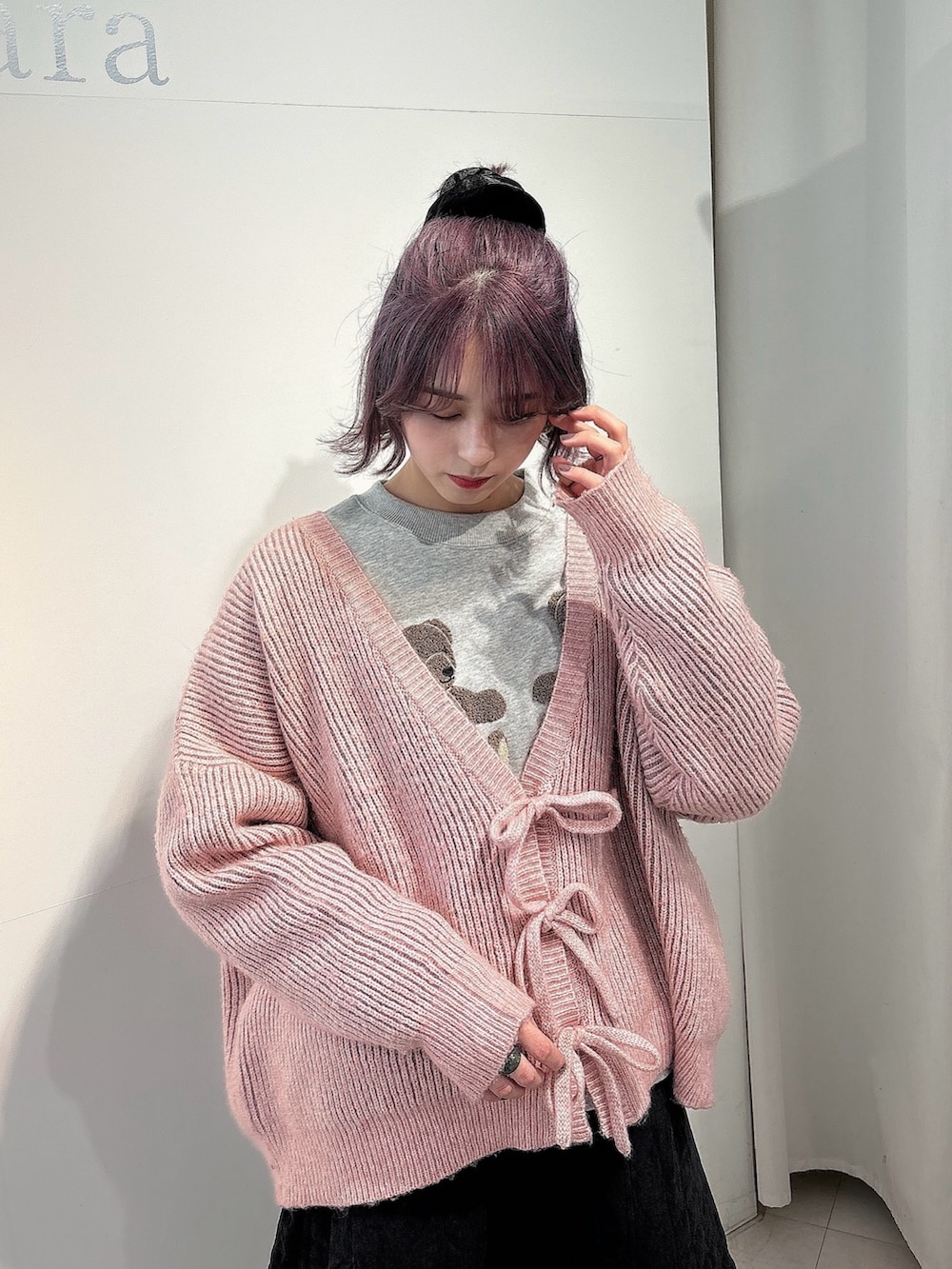 ピンク系のカーディガン/ボレロ、ブラック系のスカート、ブラック系のスニーカーを着用したレディースの冬コーディネートの3枚目の写真