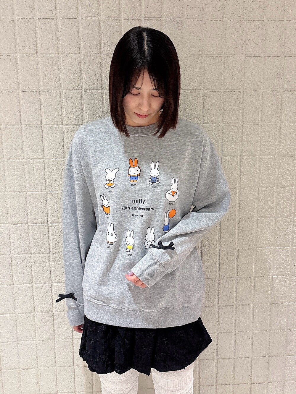 グレー系のスウェット、ブラック系のスカート、ホワイト系のその他パンツを着用したレディースの冬コーディネートの3枚目の写真