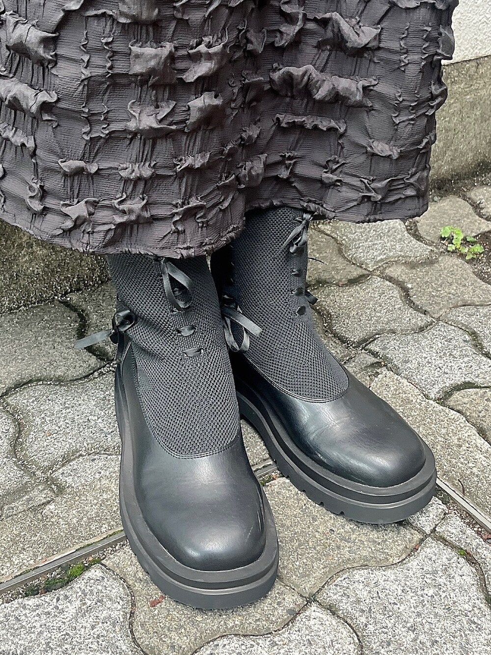 ブラック系のワンピース、ブラック系のブーツ、ブルー系のカーディガン/ボレロを着用したレディースの秋コーディネートの3枚目の写真