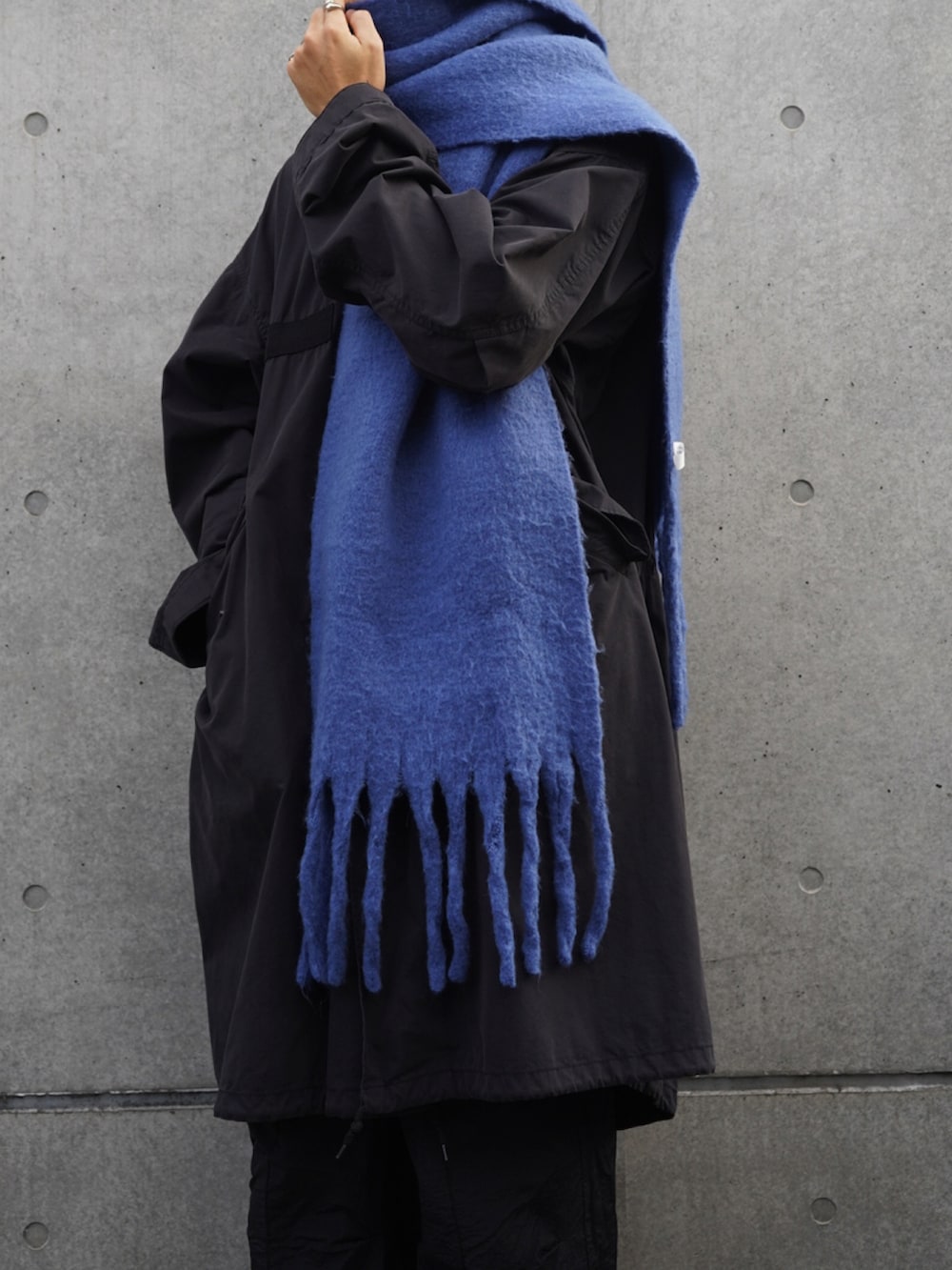 ブラック系のモッズコート、ブラック系のカーゴパンツ、ブルー系のマフラーを着用したメンズの秋コーディネートの3枚目の写真
