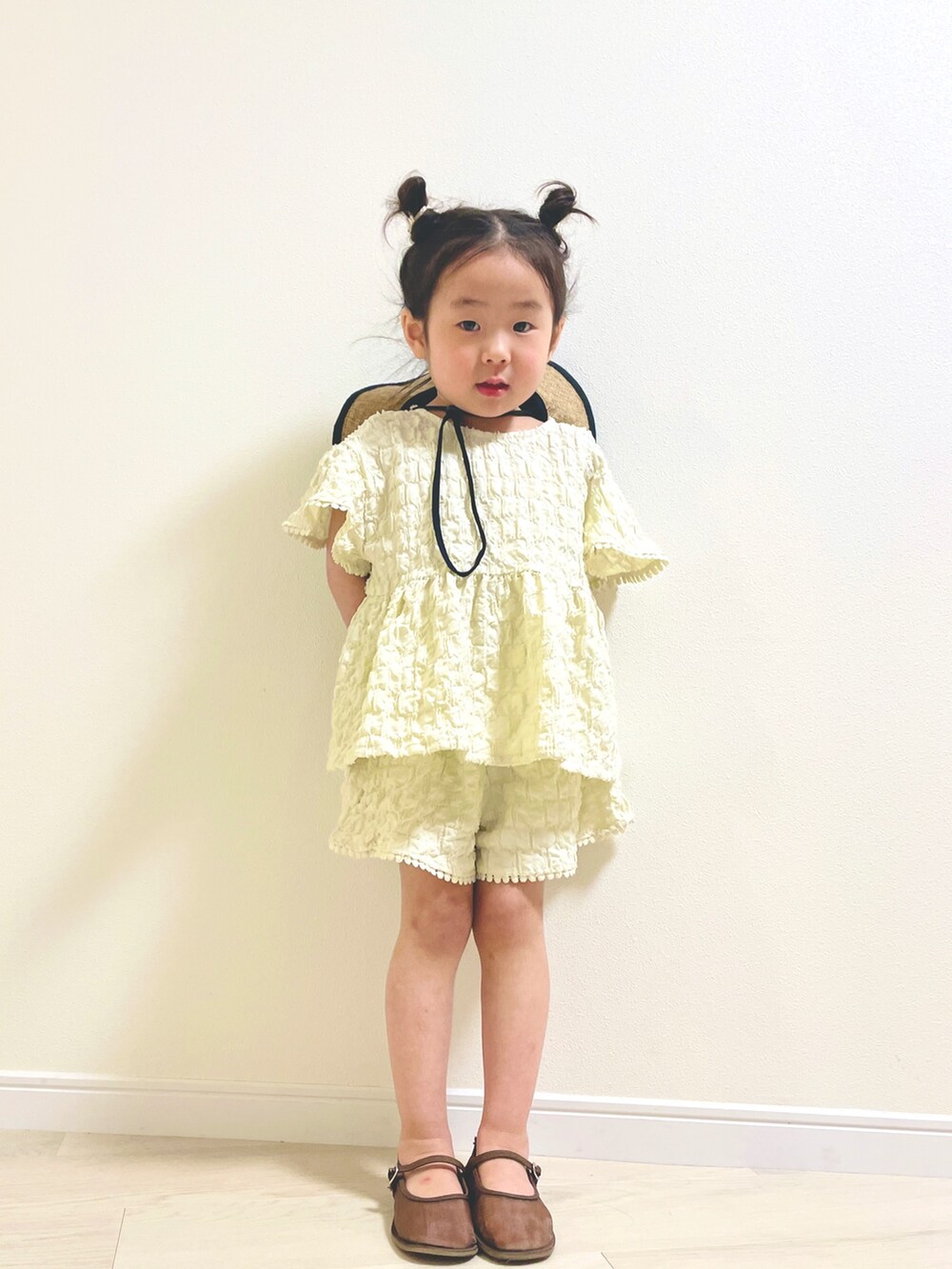 ホワイト系のセットアップ、ブラウン系のパンプスを着用したキッズの春コーディネートの2枚目の写真