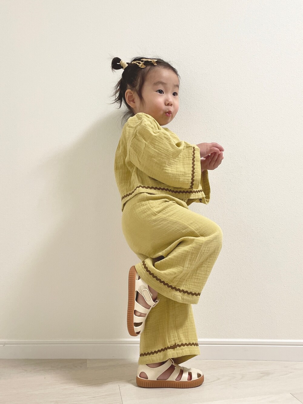 ホワイト系のサンダル、イエロー系のその他ベビーウェアを着用したキッズの冬コーディネートの2枚目の写真