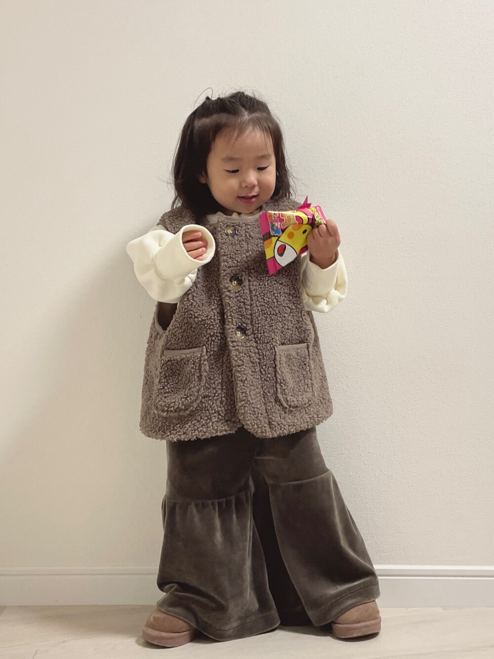 ブラウン系のベスト、ブラウン系のブーツ、ホワイト系のその他ベビーウェアを着用したキッズの冬コーディネートの2枚目の写真