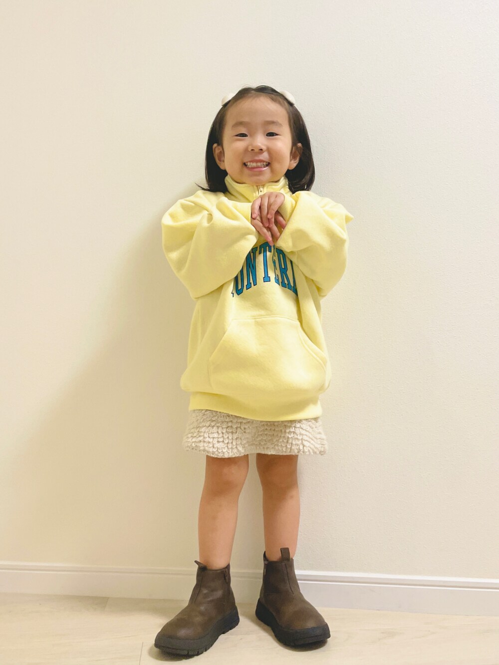 イエロー系のスウェット、ブラウン系のブーツ、ホワイト系のその他ベビーウェアを着用したキッズの秋コーディネートの2枚目の写真