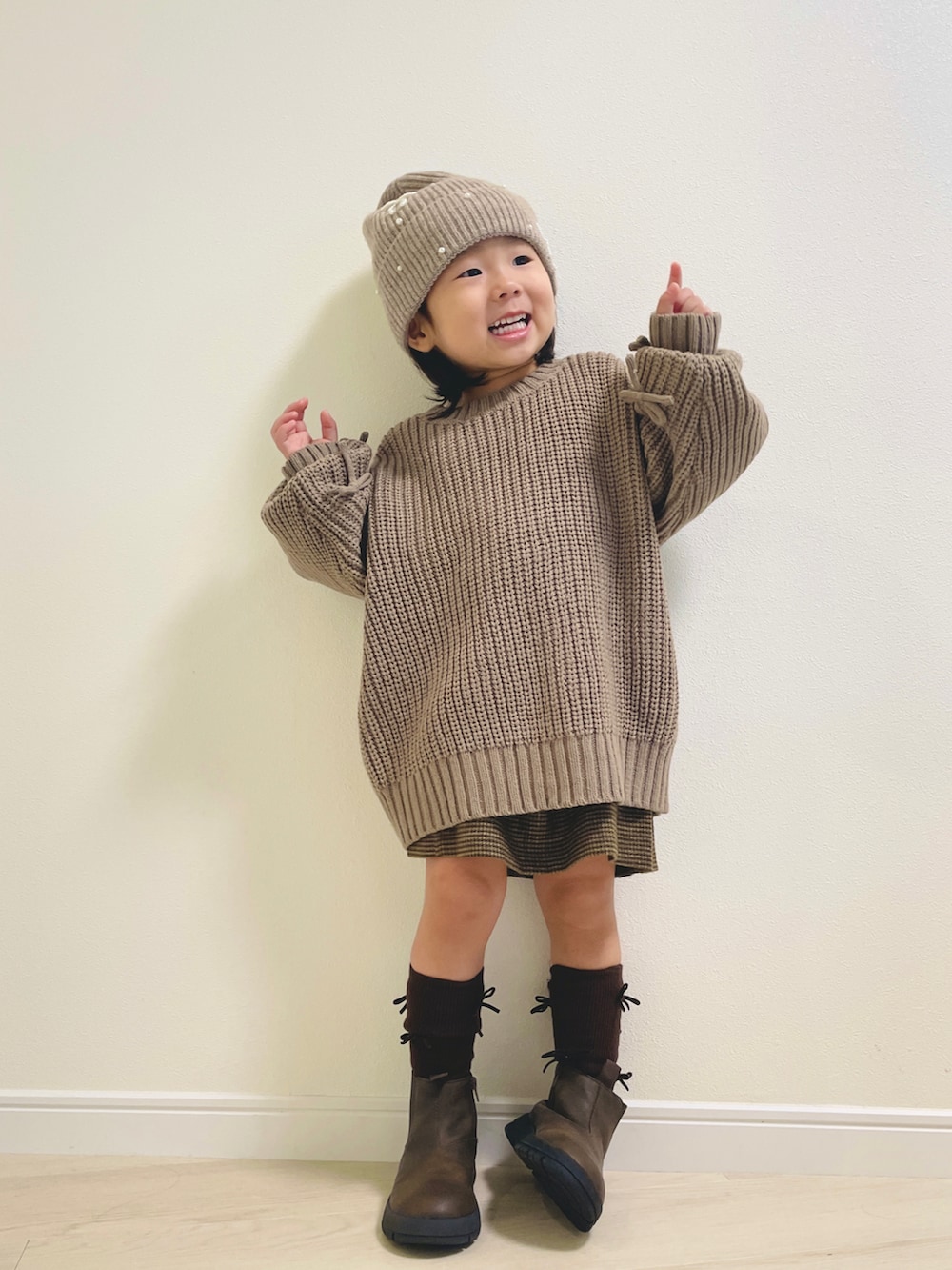 ベージュ系のニット/セーター、ブラウン系のブーツ、ベージュ系のニットキャップ/ビーニーを着用したキッズの秋コーディネートの3枚目の写真