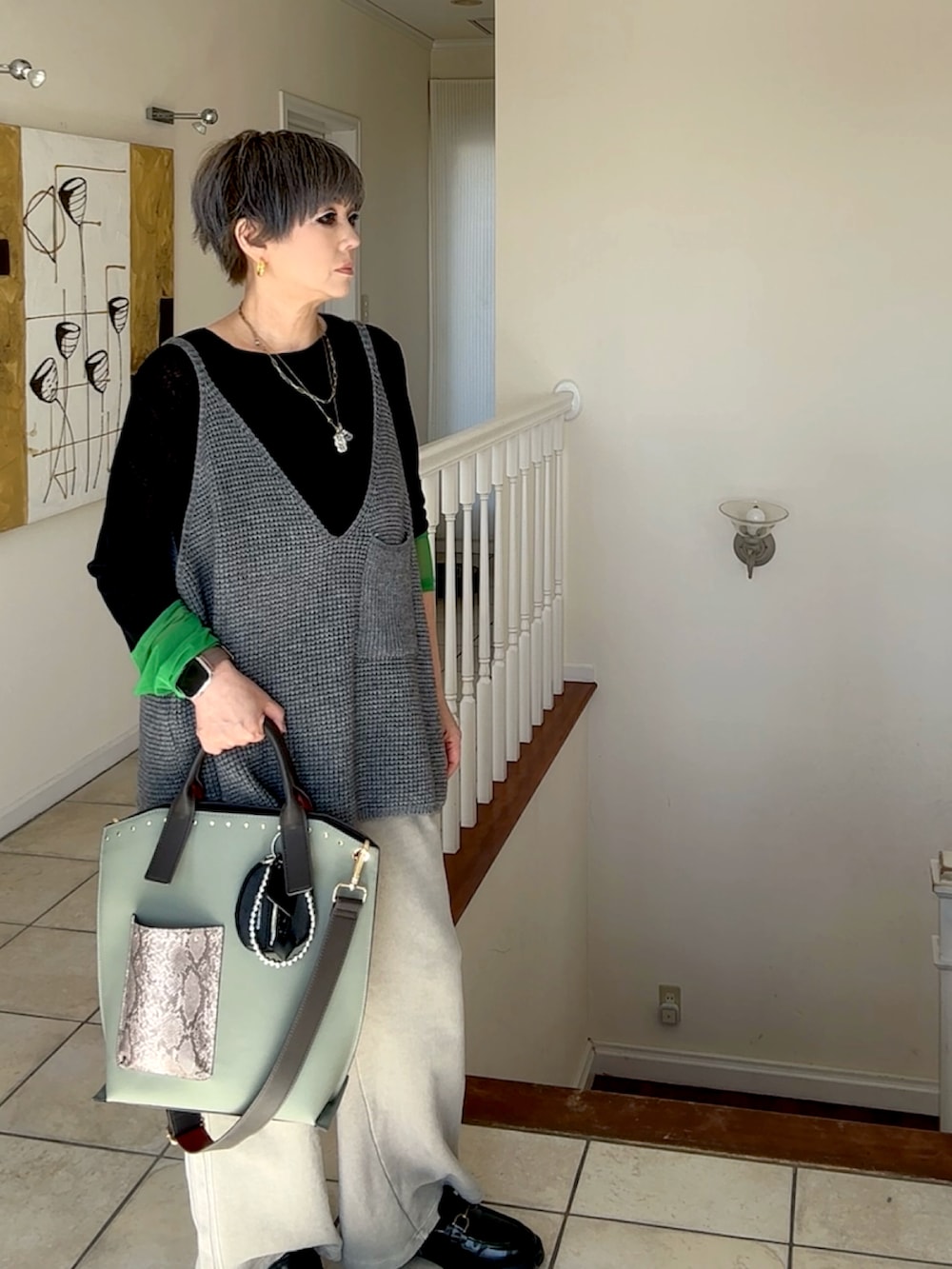 グレー系のベスト、ブラック系のTシャツ/カットソー、ベージュ系のスウェットパンツを着用したレディースの秋コーディネートの2枚目の写真