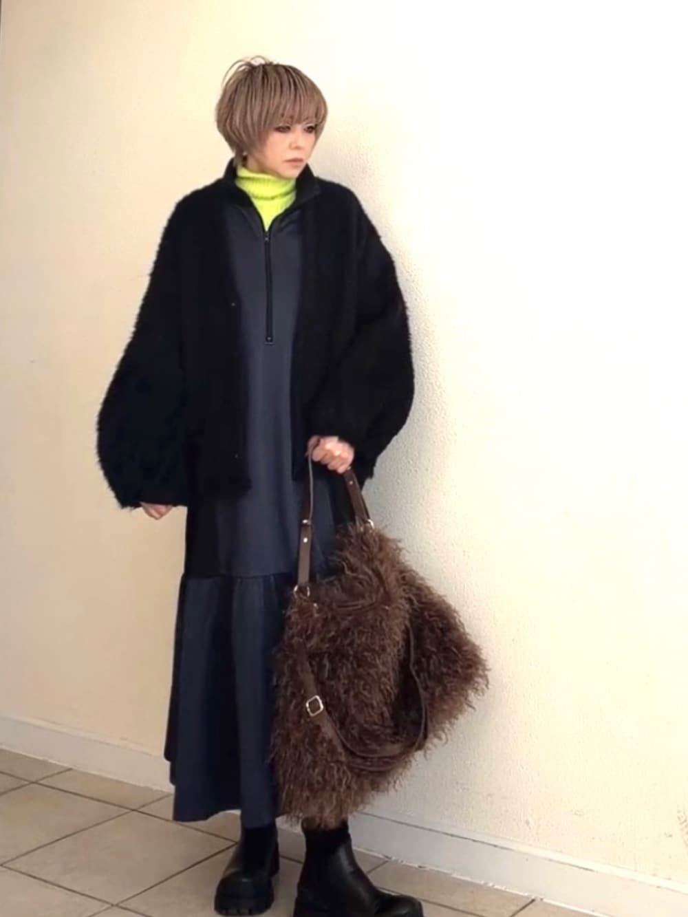 グリーン系のニット/セーター、グレー系のワンピース、ブラウン系のショルダーバッグを着用したレディースの冬コーディネートの2枚目の写真