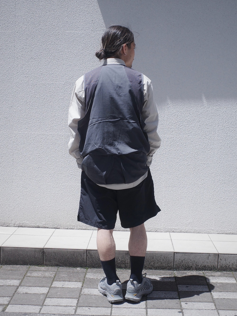 グレー系のベスト、ブラック系のその他パンツを着用したメンズの春コーディネートの3枚目の写真