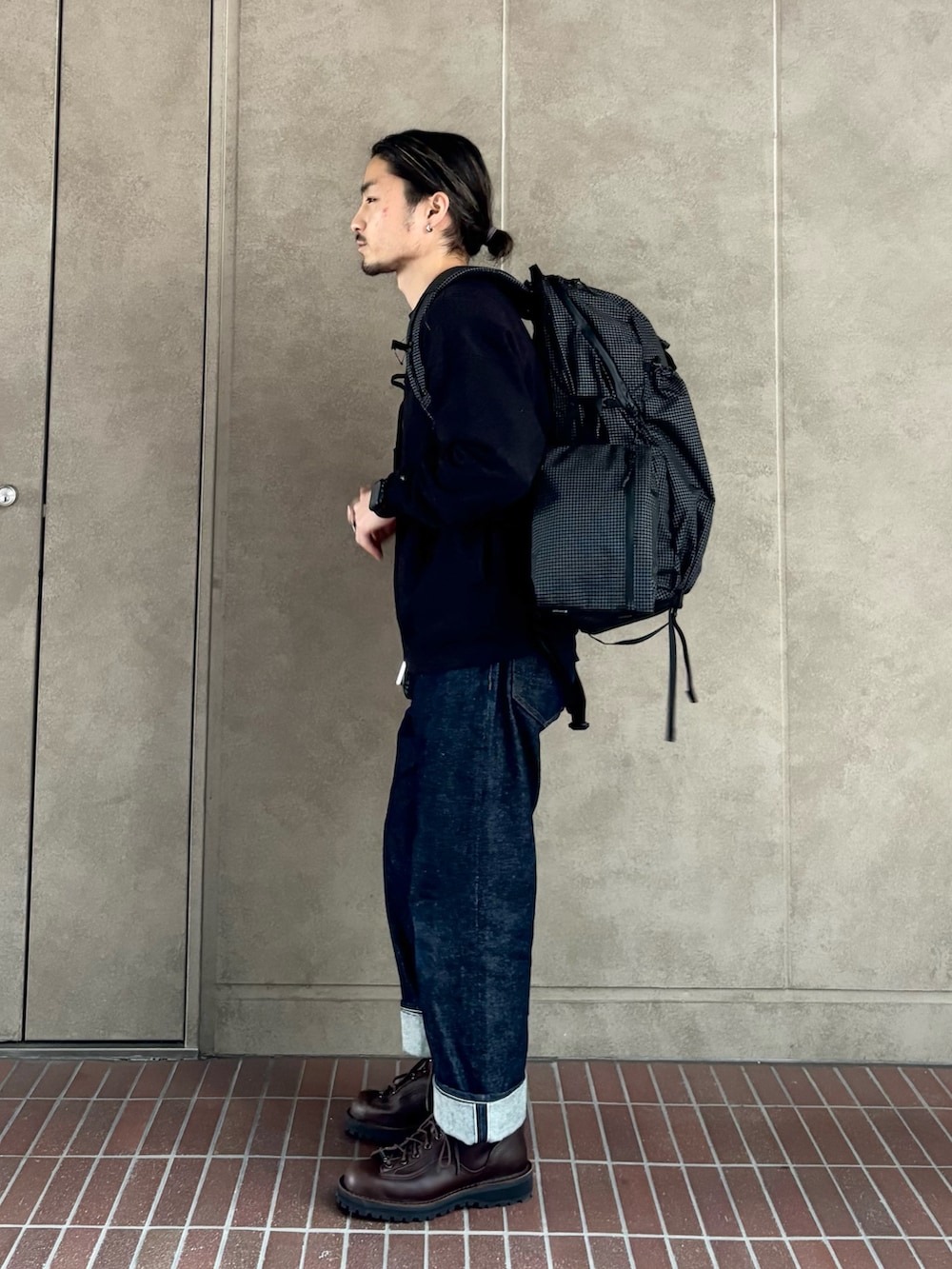 ブラック系のスウェット、ブルー系のデニムパンツ、ブラック系のバックパック/リュックを着用したメンズの冬コーディネートの4枚目の写真