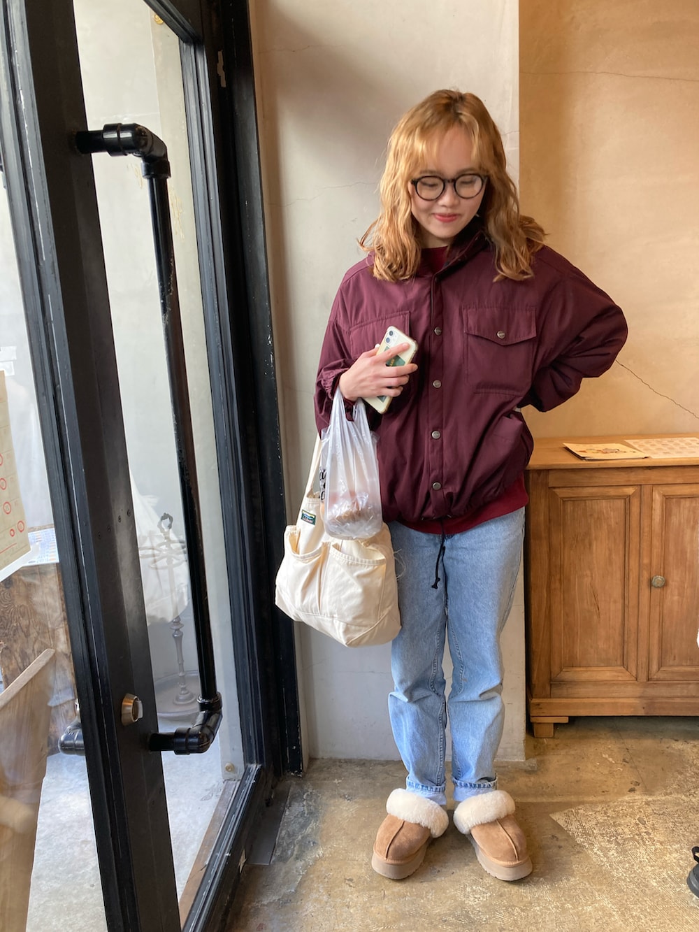 ブルー系のデニムパンツ、ブラウン系のスリッポン、ホワイト系のトートバッグを着用したレディースの秋コーディネートの3枚目の写真